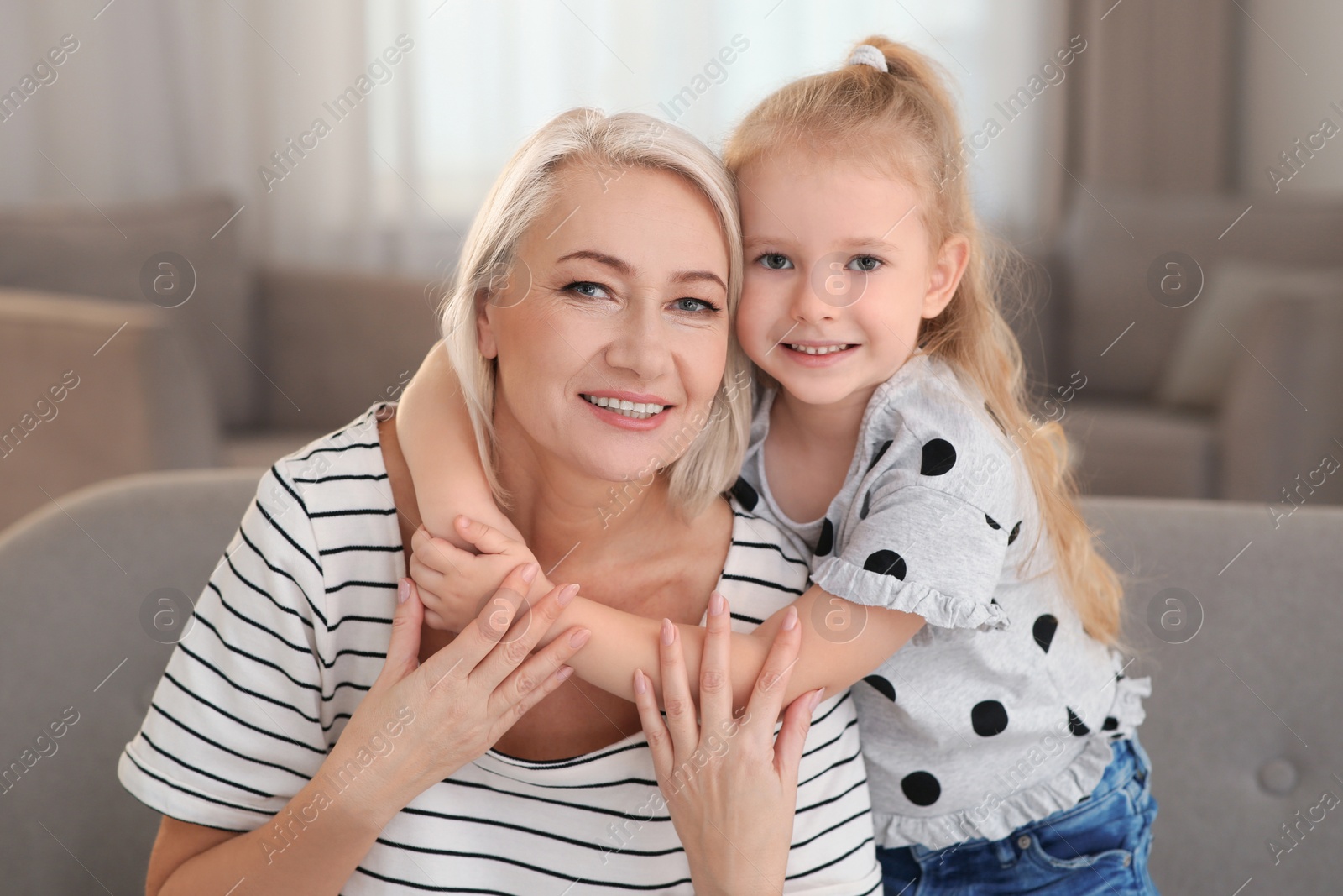 Photo of Portrait of mature woman and her granddaughter on sofa in living room