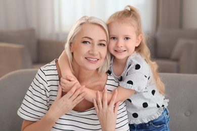 Photo of Portrait of mature woman and her granddaughter on sofa in living room