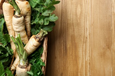 Photo of Tasty fresh ripe parsnips in wicker basket on wooden table, top view. Space for text