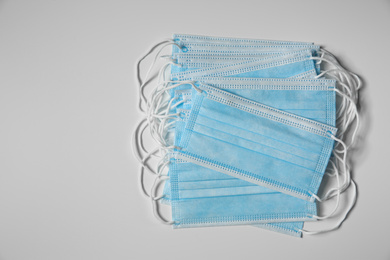 Photo of Disposable face masks on light background, flat lay. Protective measures during coronavirus quarantine