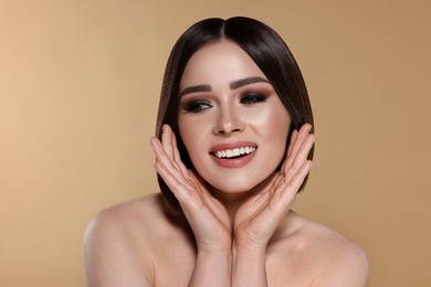 Image of Portrait of pretty young woman with brown hair smiling on beige background