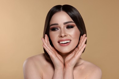 Portrait of pretty young woman with brown hair smiling on beige background