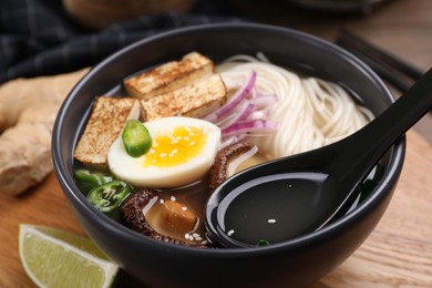 Photo of Delicious vegetarian ramen in bowl on wooden table, closeup