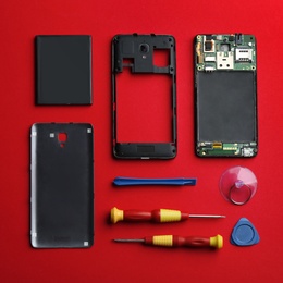 Photo of Flat lay composition with broken mobile phone and repair tools on red background