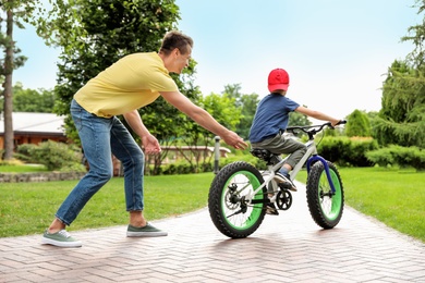 Dad teaching son to ride bicycle outdoors