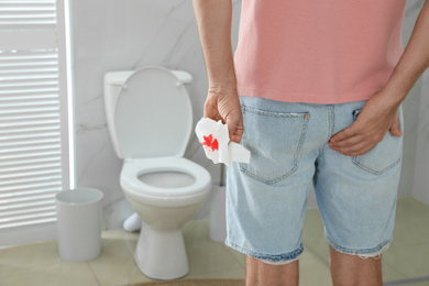 Photo of Man holding toilet paper with blood stain in rest room, closeup. Hemorrhoid concept
