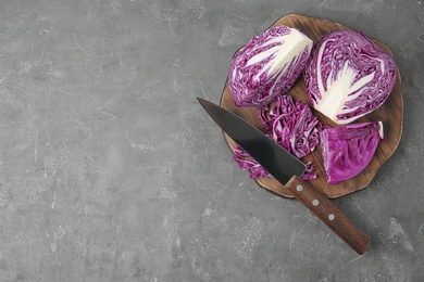 Photo of Fresh red cabbage, knife and cutting board on grey table