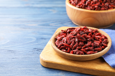 Dry goji berries on blue wooden table, closeup