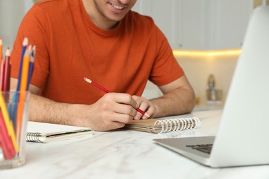 Photo of Man drawing in notebook at online lesson indoors, closeup. Distance learning