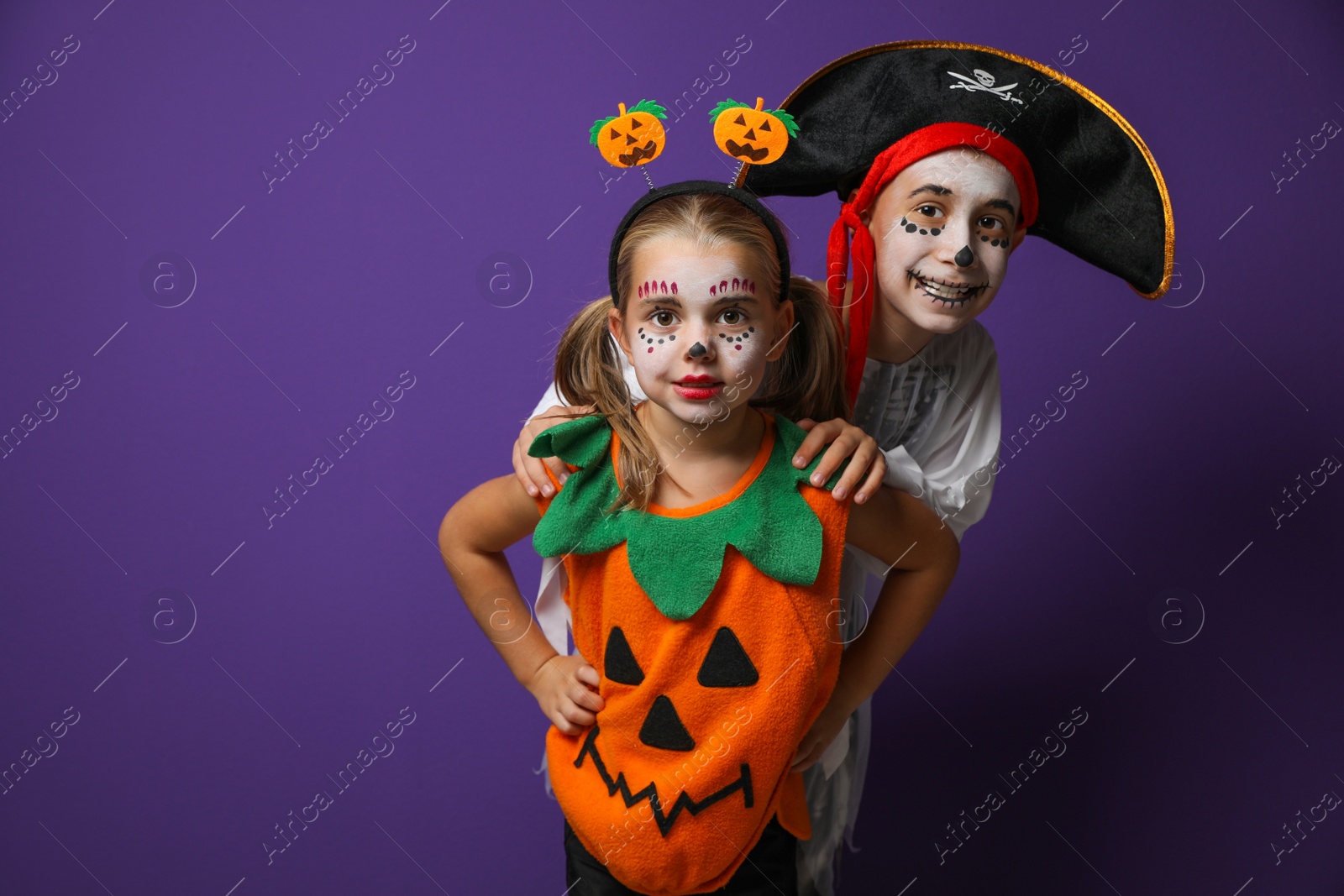 Photo of Cute little kids wearing Halloween costumes on purple background