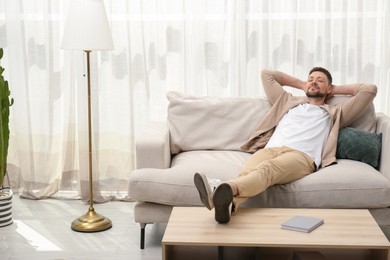 Photo of Handsome man relaxing on sofa at home