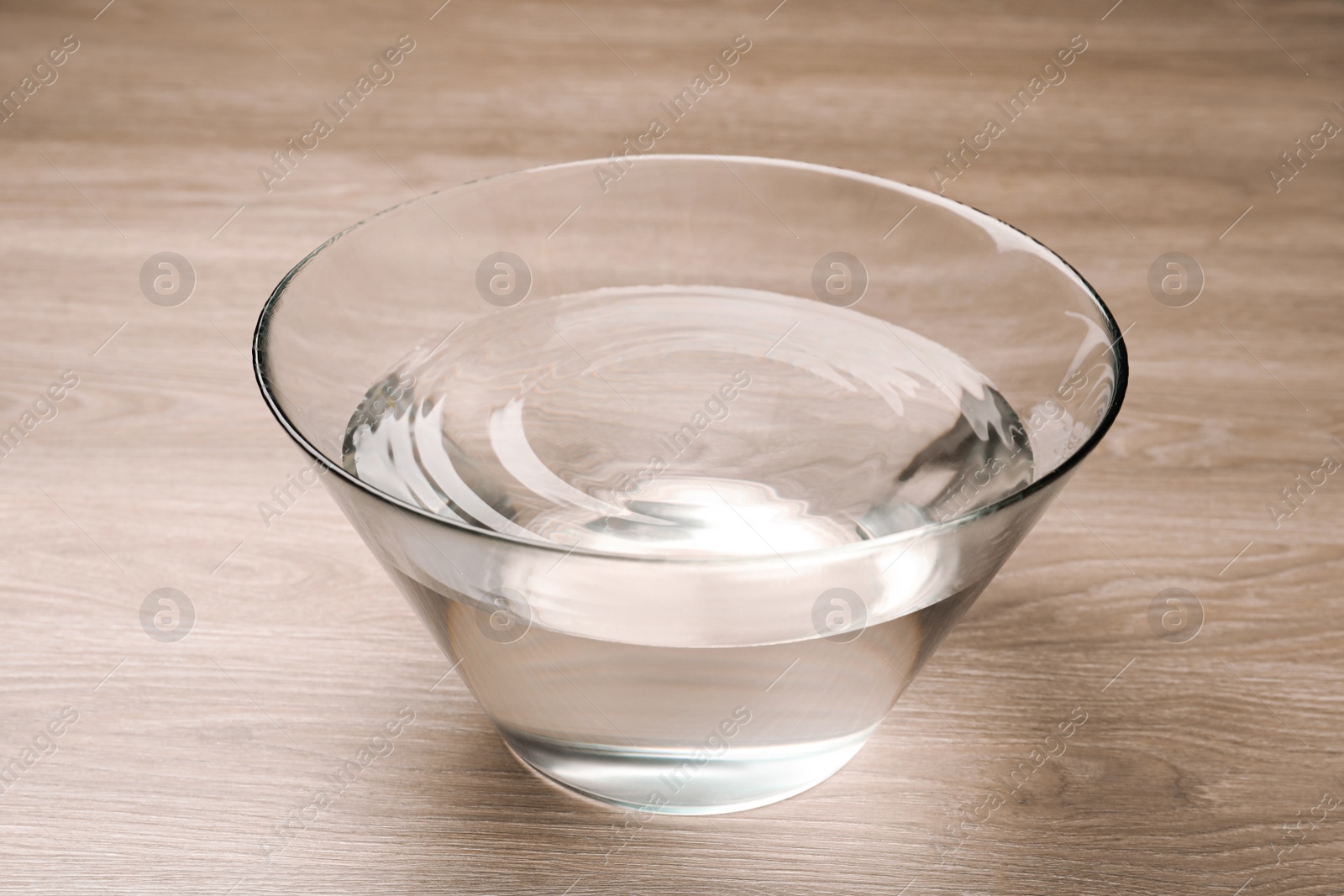 Photo of Glass bowl with water on wooden table