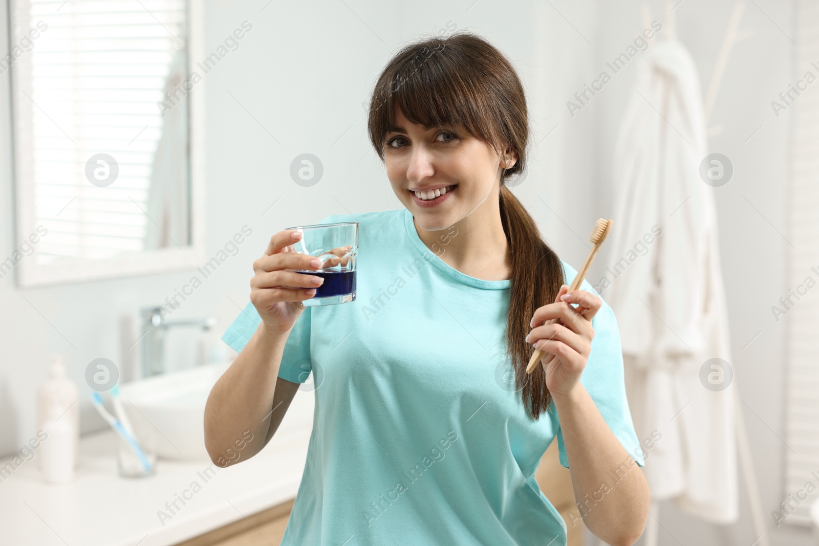 Photo of Young woman with mouthwash and toothbrush in bathroom