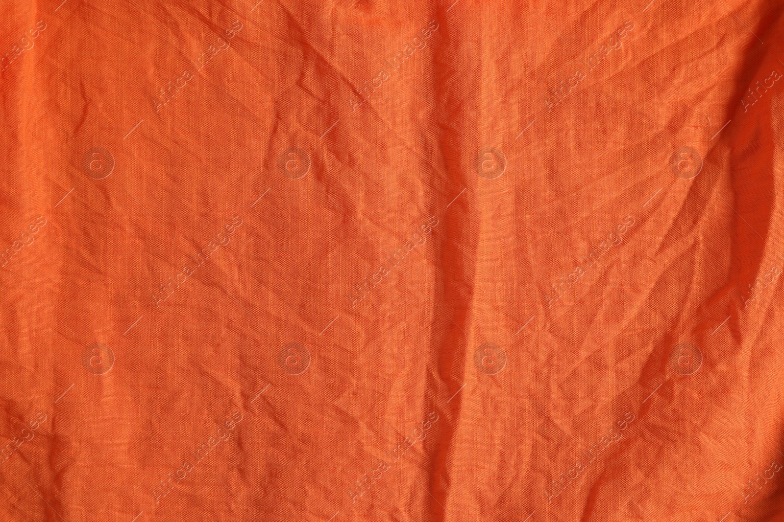 Photo of Crumpled orange fabric as background, top view