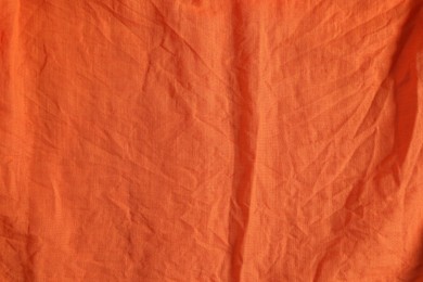 Crumpled orange fabric as background, top view