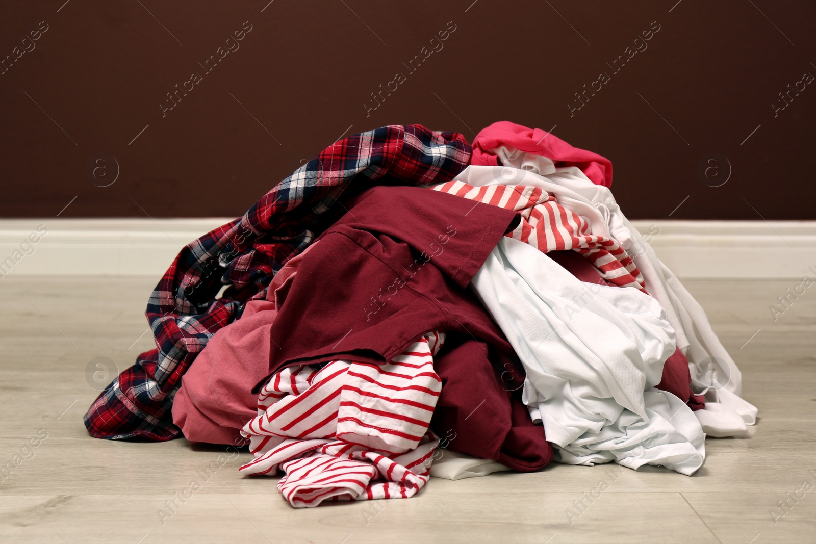 Photo of Pile of dirty clothes on floor near brown wall indoors