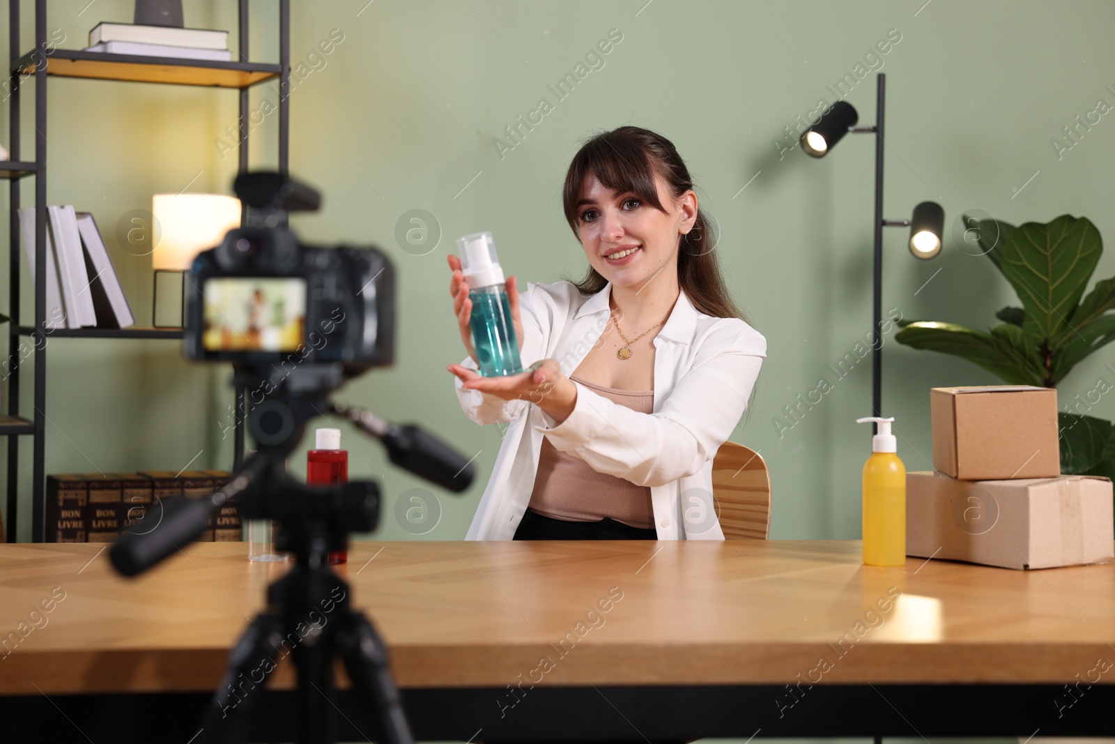 Photo of Beauty blogger recording video while showing cosmetic products at home