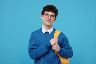 Portrait of student with backpack on light blue background