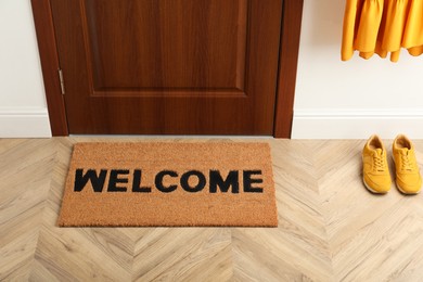 Door mat with word Welcome on wooden floor in hall