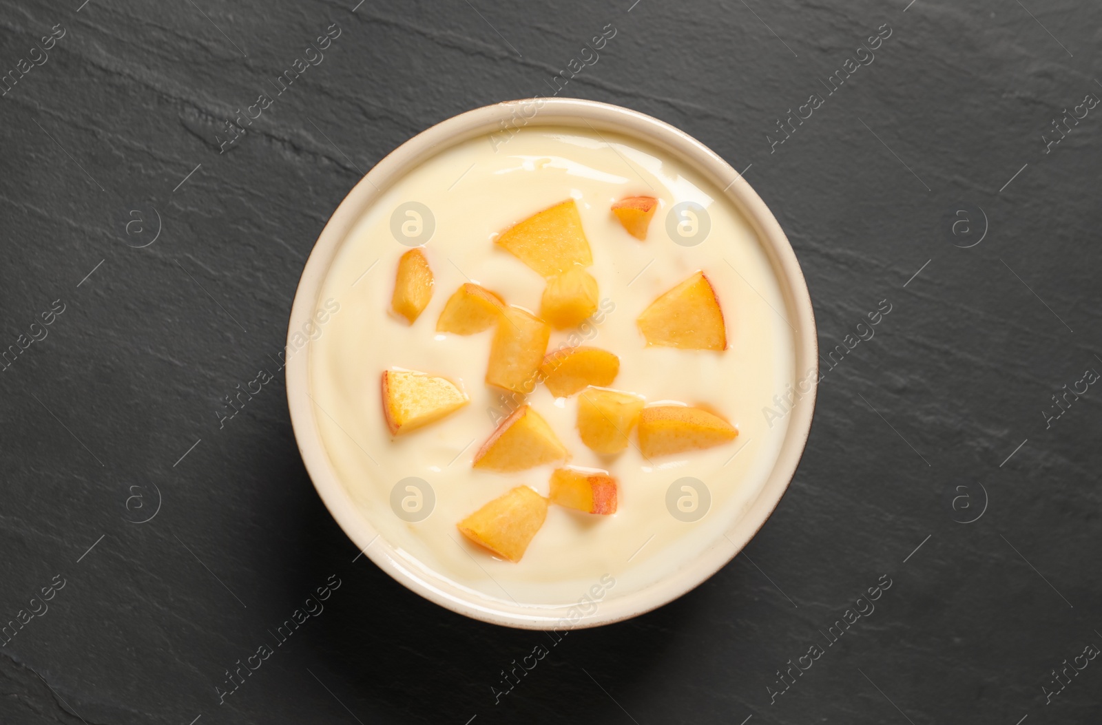 Photo of Delicious yogurt with fresh peach on black table, top view