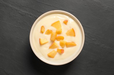 Photo of Delicious yogurt with fresh peach on black table, top view