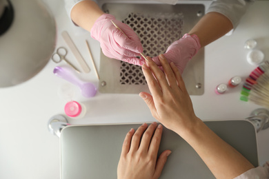 Photo of Professional manicurist working with client in beauty salon, top view