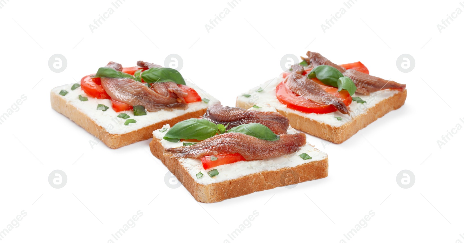 Photo of Delicious sandwiches with cream cheese, anchovies, tomatoes and basil on white background