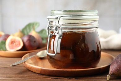 Jar of tasty sweet fig jam on wooden table