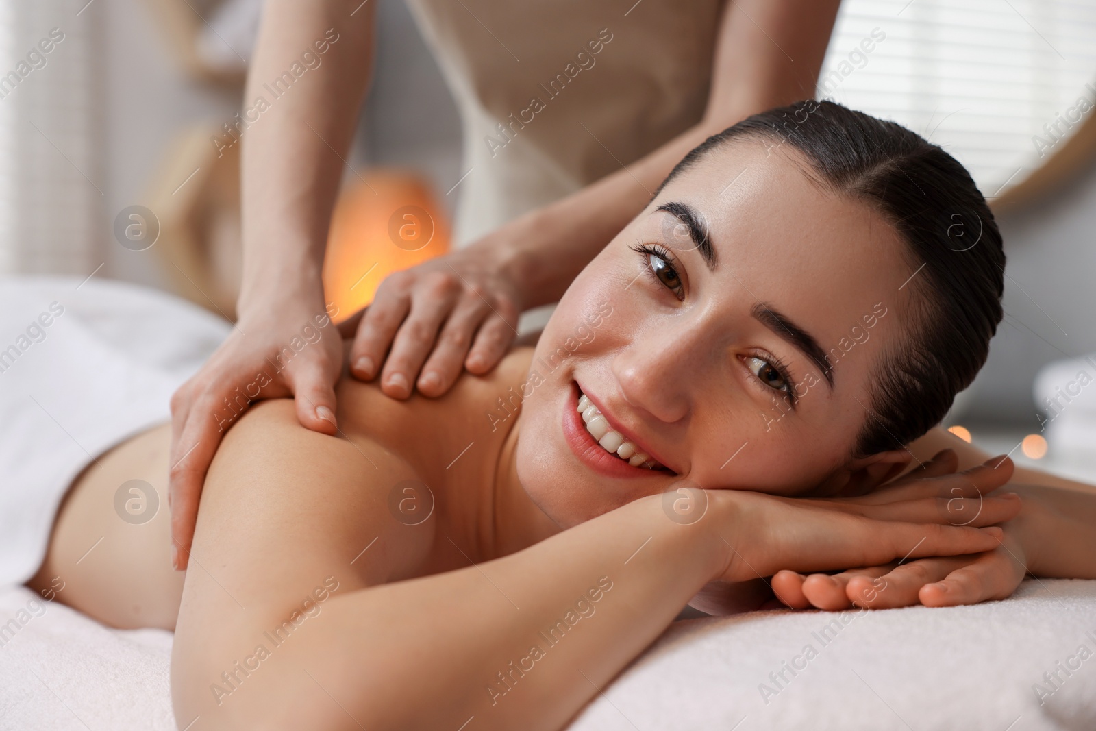 Photo of Woman receiving back massage on couch in spa salon