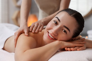 Woman receiving back massage on couch in spa salon