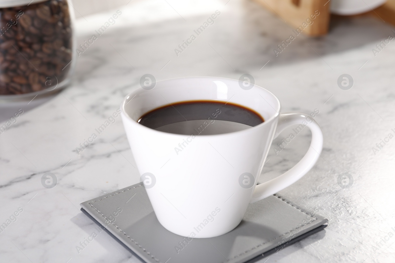 Photo of Delicious coffee in cup on white marble table, closeup