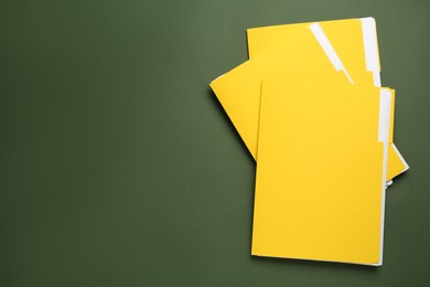 Photo of Yellow files with documents on dark green background, top view. Space for text