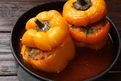 Photo of Tasty stuffed peppers in pan on wooden table, closeup