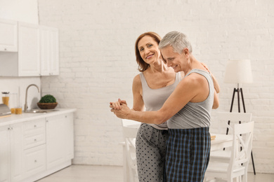 Photo of Happy senior couple dancing together in kitchen