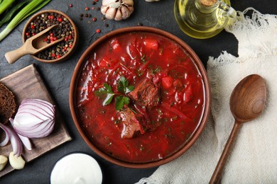 Photo of Stylish brown clay bowl with Ukrainian borsch served on black table, flat lay