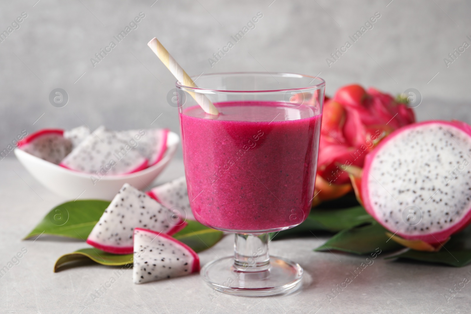 Photo of Delicious pitahaya smoothie and fresh fruits on light grey table