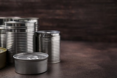 Photo of Many closed tin cans on brown table. Space for text
