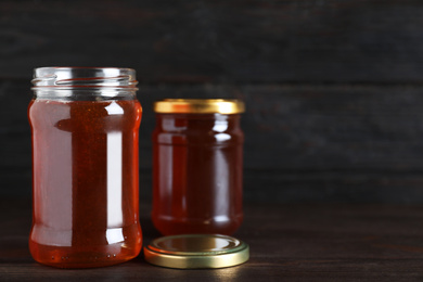 Jars of organic honey on wooden table against dark background. Space for text