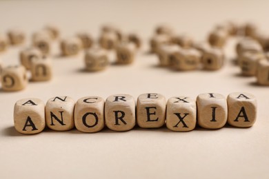 Photo of Word Anorexia made of wooden cubes with letters on beige table