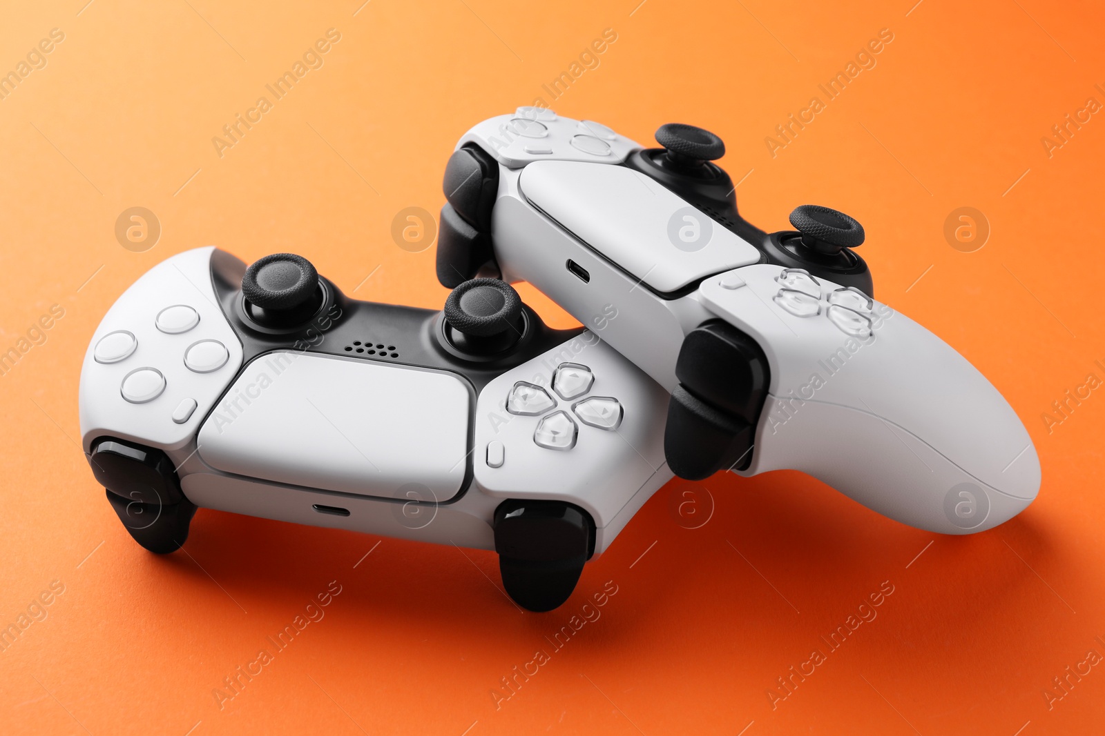 Photo of Two wireless game controllers on orange background