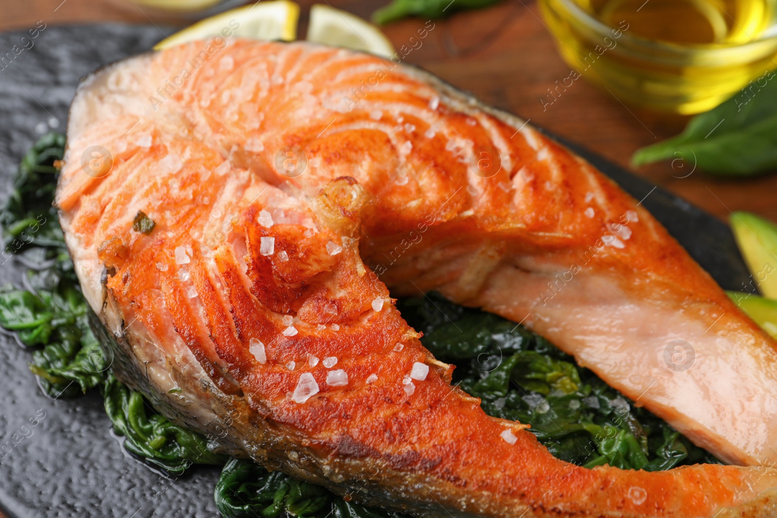 Photo of Tasty salmon with spinach served on table, closeup