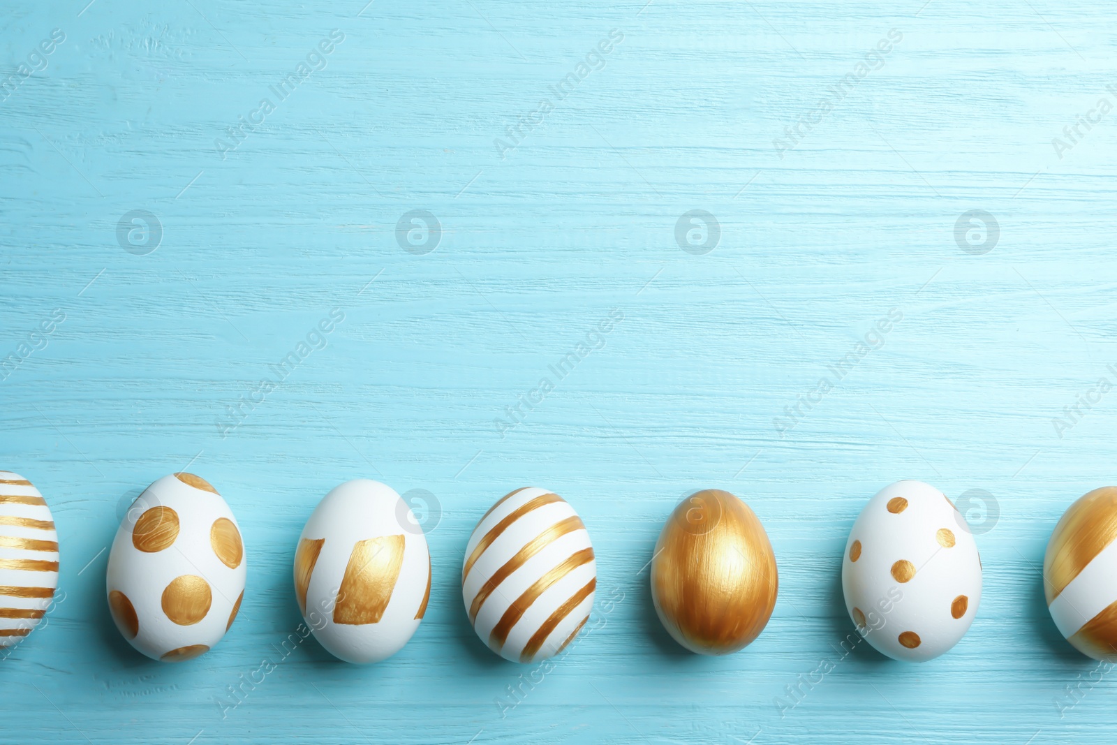 Photo of Set of traditional Easter eggs decorated with golden paint on wooden background, top view. Space for text