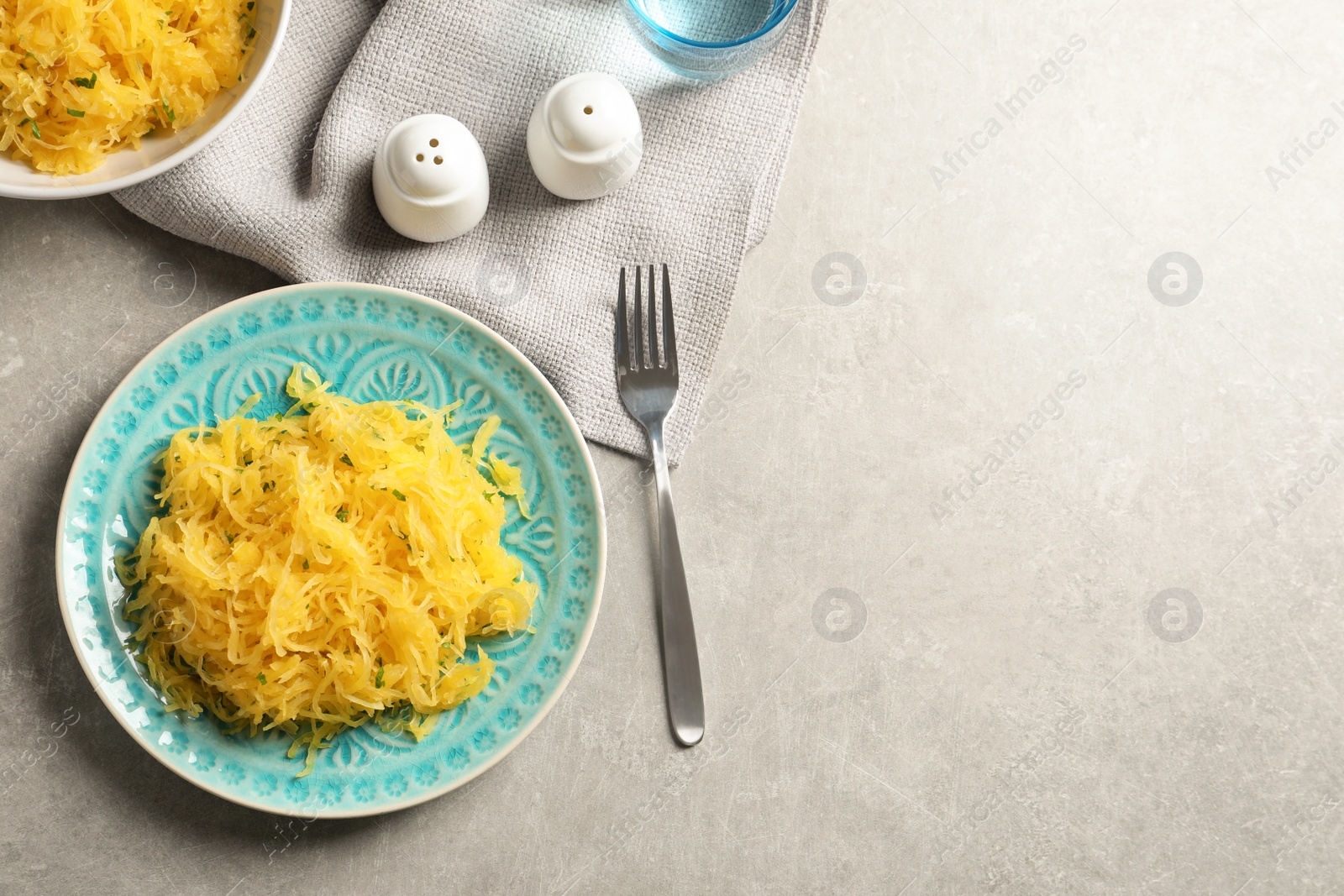 Photo of Flat lay composition with plate of cooked spaghetti squash on gray background. Space for text