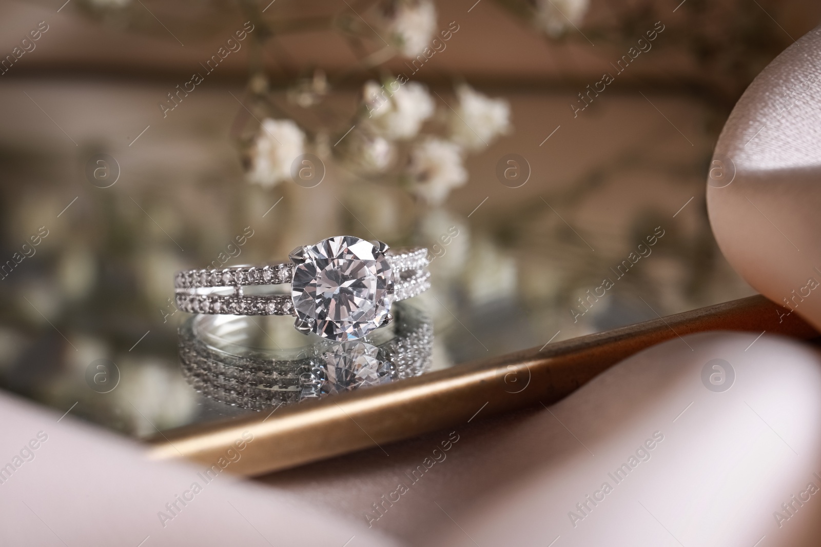 Photo of Elegant jewelry. Stylish presentation of luxury ring on mirror, closeup