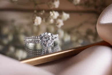 Photo of Elegant jewelry. Stylish presentation of luxury ring on mirror, closeup