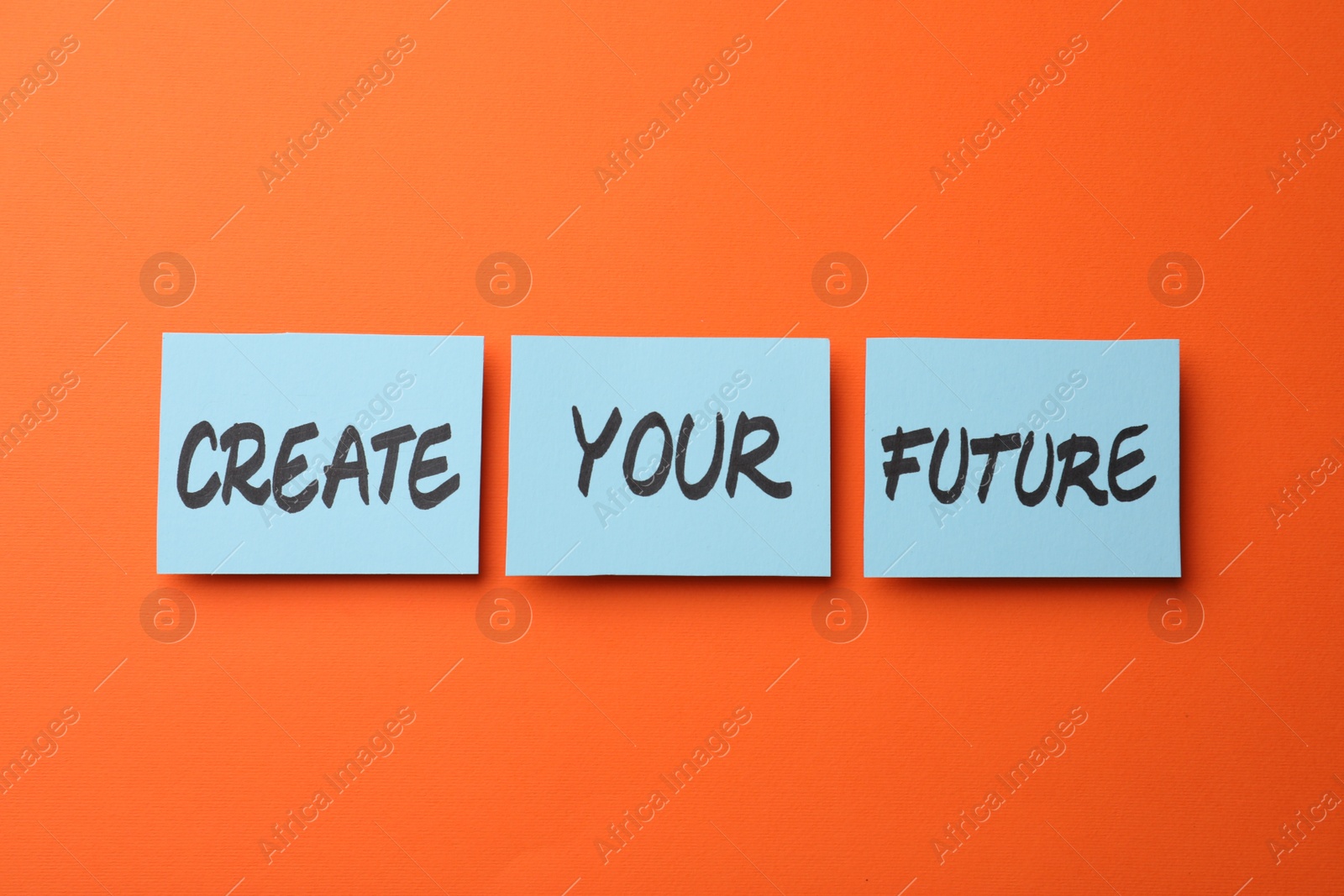 Photo of Motivational phrase Create Your Future made of sticky notes with words on orange background