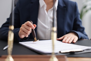 Photo of Notary sealing document at table in office, closeup