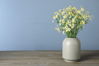 Photo of Vase with beautiful chamomile flowers on wooden table. Space for text