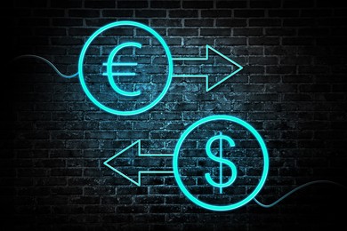 Image of Money exchange neon sign. Light blue arrows, euro and dollar symbols on brick wall