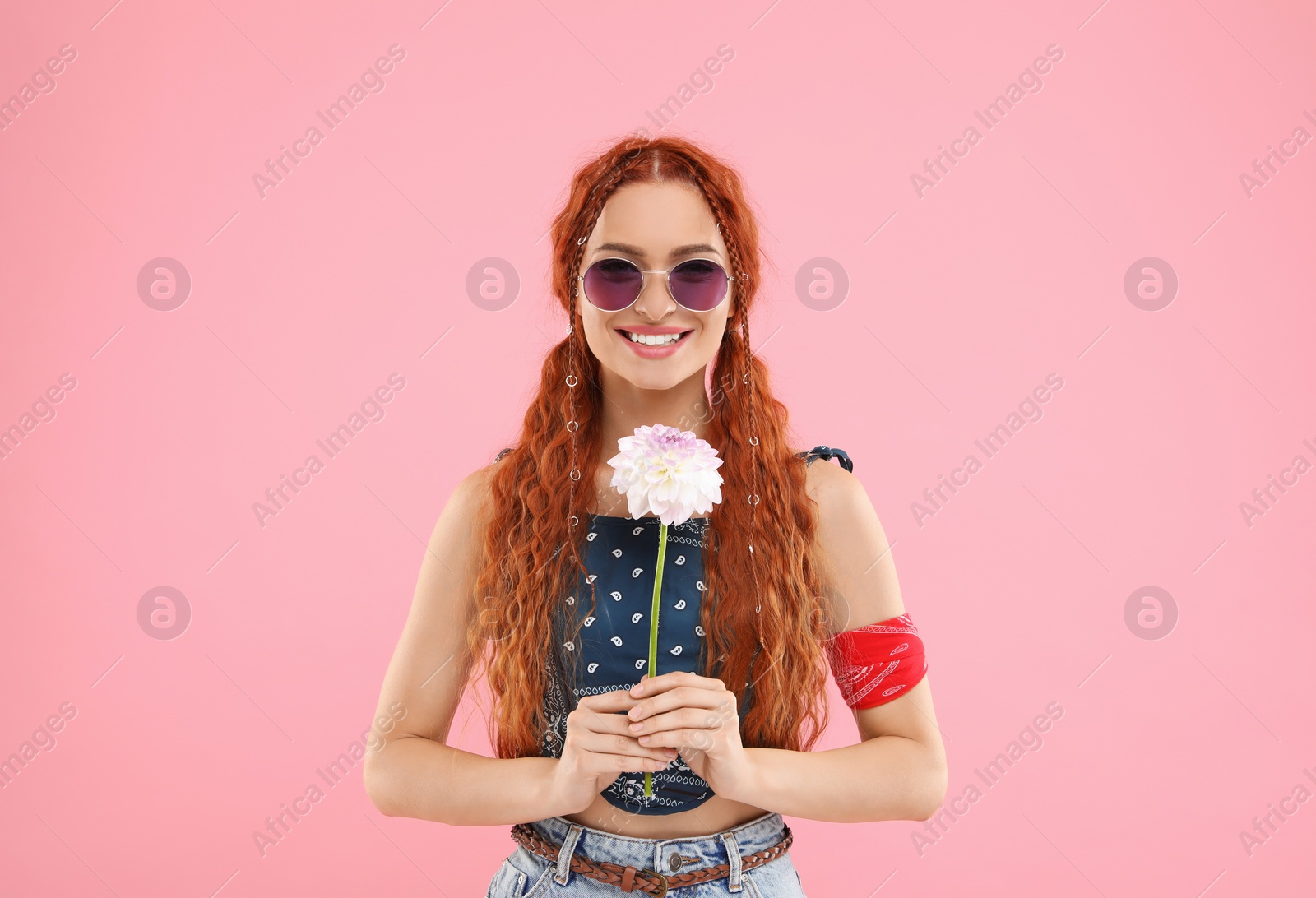 Photo of Stylish young hippie woman with dahlia flower on pink background